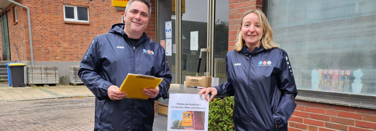 Zwei Mitglieder der ABS an einem Stehtisch vor der Postfiliale.