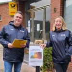 Zwei Mitglieder der ABS an einem Stehtisch vor der Postfiliale.