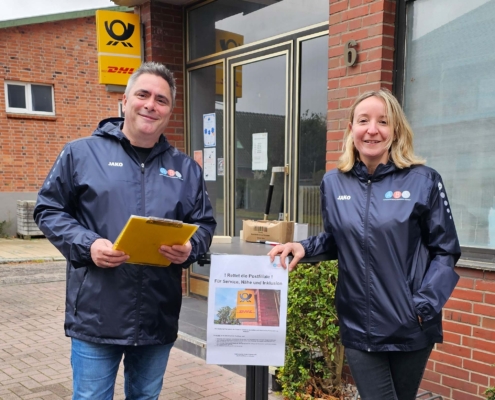 Zwei Mitglieder der ABS an einem Stehtisch vor der Postfiliale.